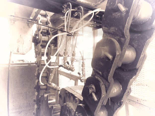 Directional spray nozzles on sand dryer drive chain